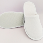 Белые гостиничные тапочки на фоне полотенца